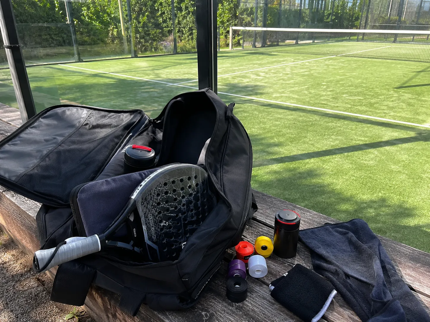 کیف Padel باز با اورگریپ، راکت و لوازم جانبی در کنار زمین